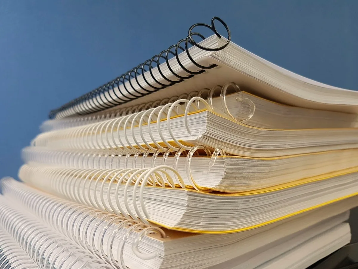 A stack of spiral-bound notebooks seen from the edge, showing the wire coils and the stacked blocks of pages